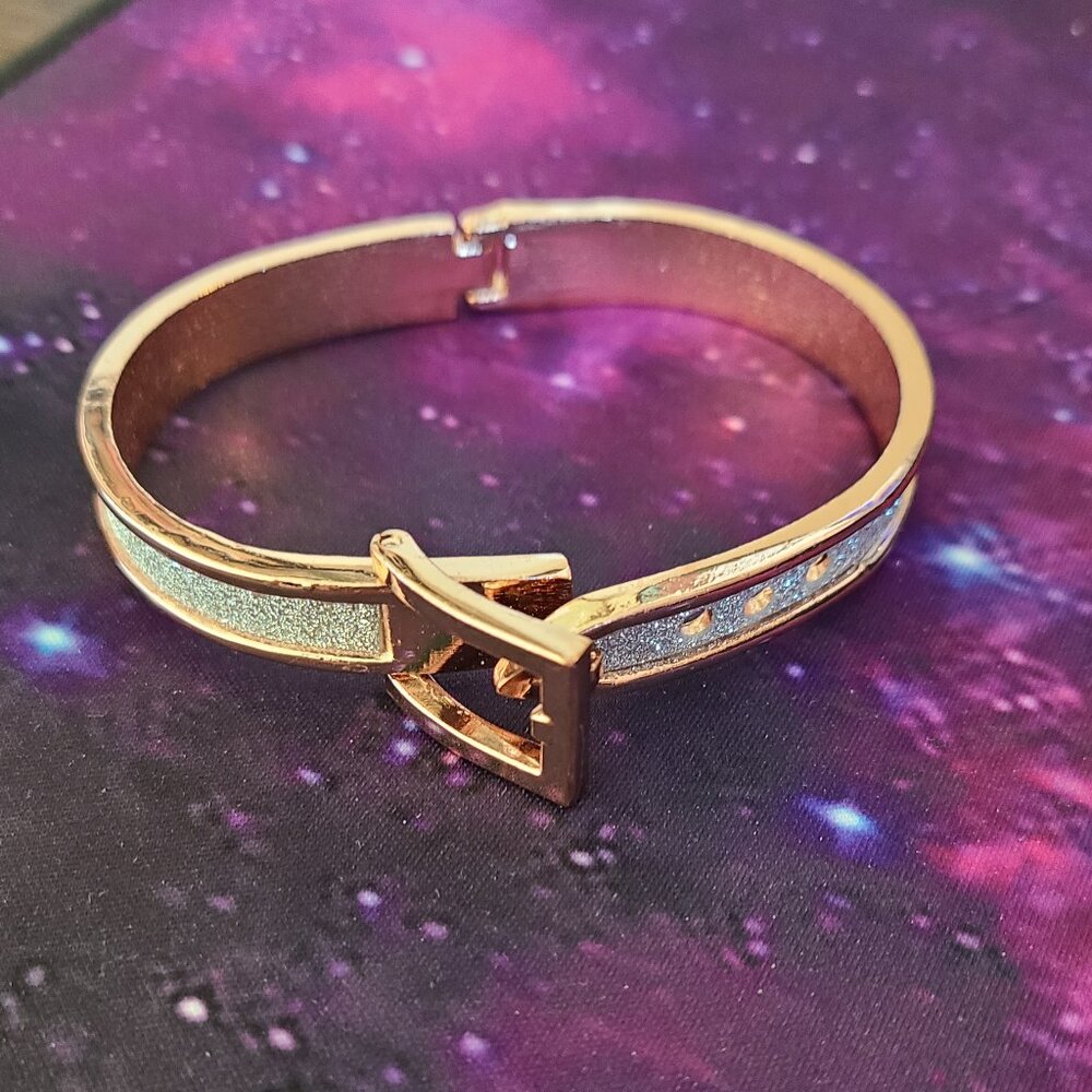 Rose gold-tone belt buckle bangle bracelets with glitter accents.